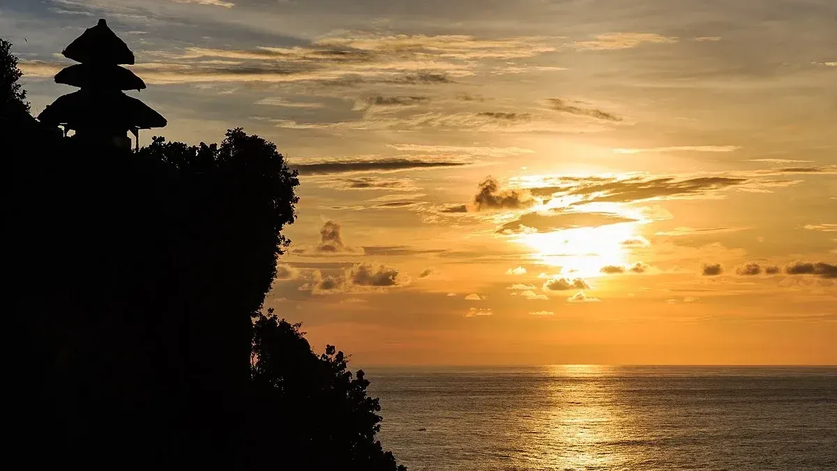 Bali clifftop temple silhouetted against a sunset ocean